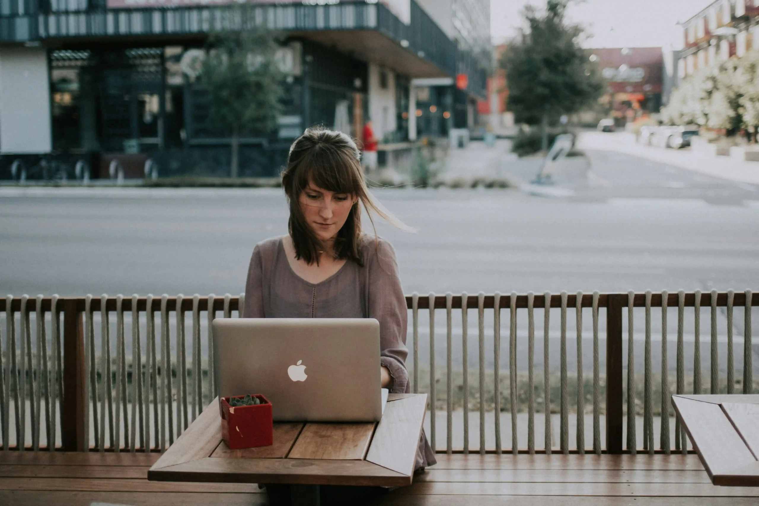 female looks focused remote working at an outdoor cafe.