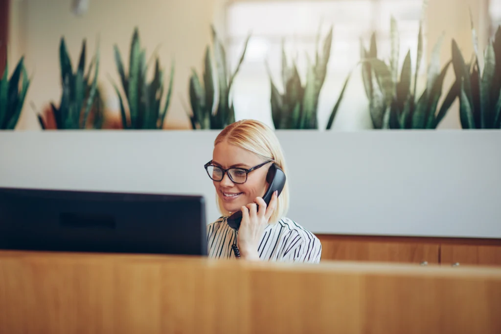 happy female receptionist uses voip technology to handle an incoming call.