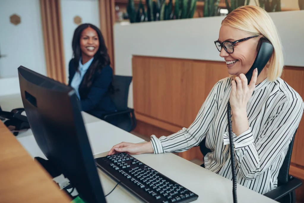 Two female employees enjoy easy increased productivity through modern telecoms.