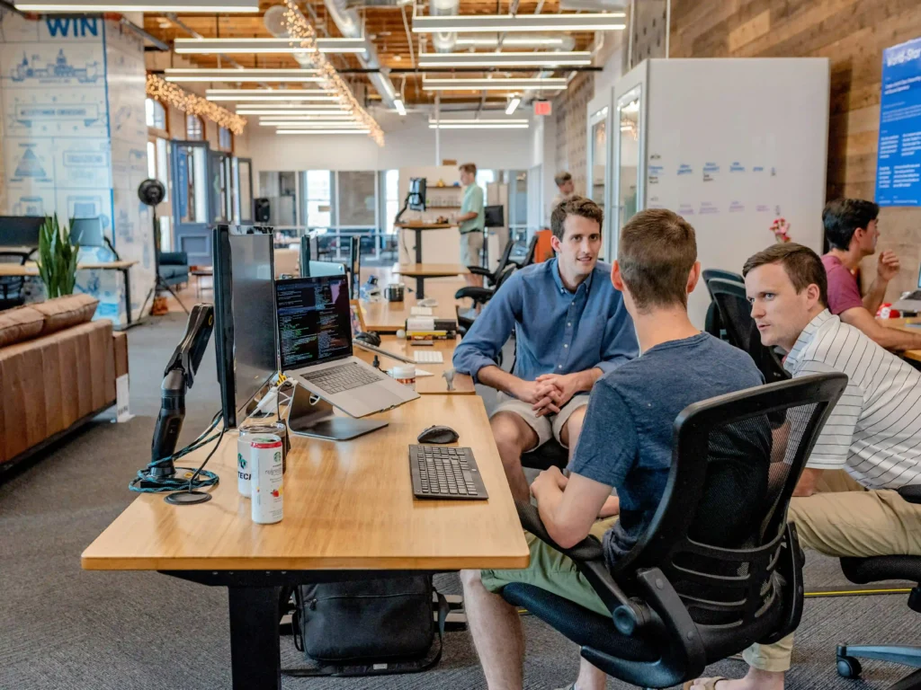 A young sales team gathers around a desk using modern tools. 